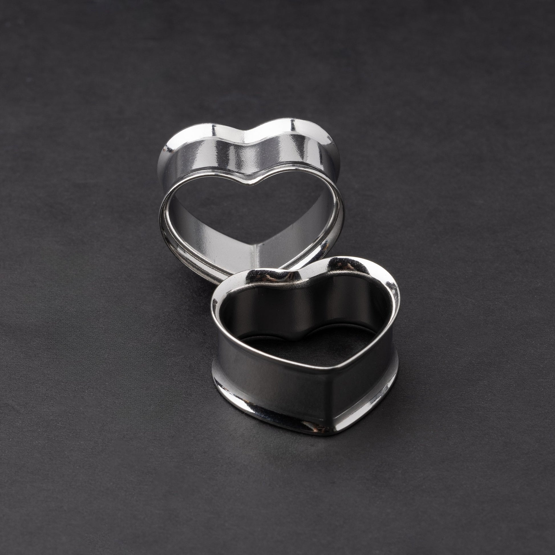Heart-shaped tunnels in silver, displayed on a dark background.