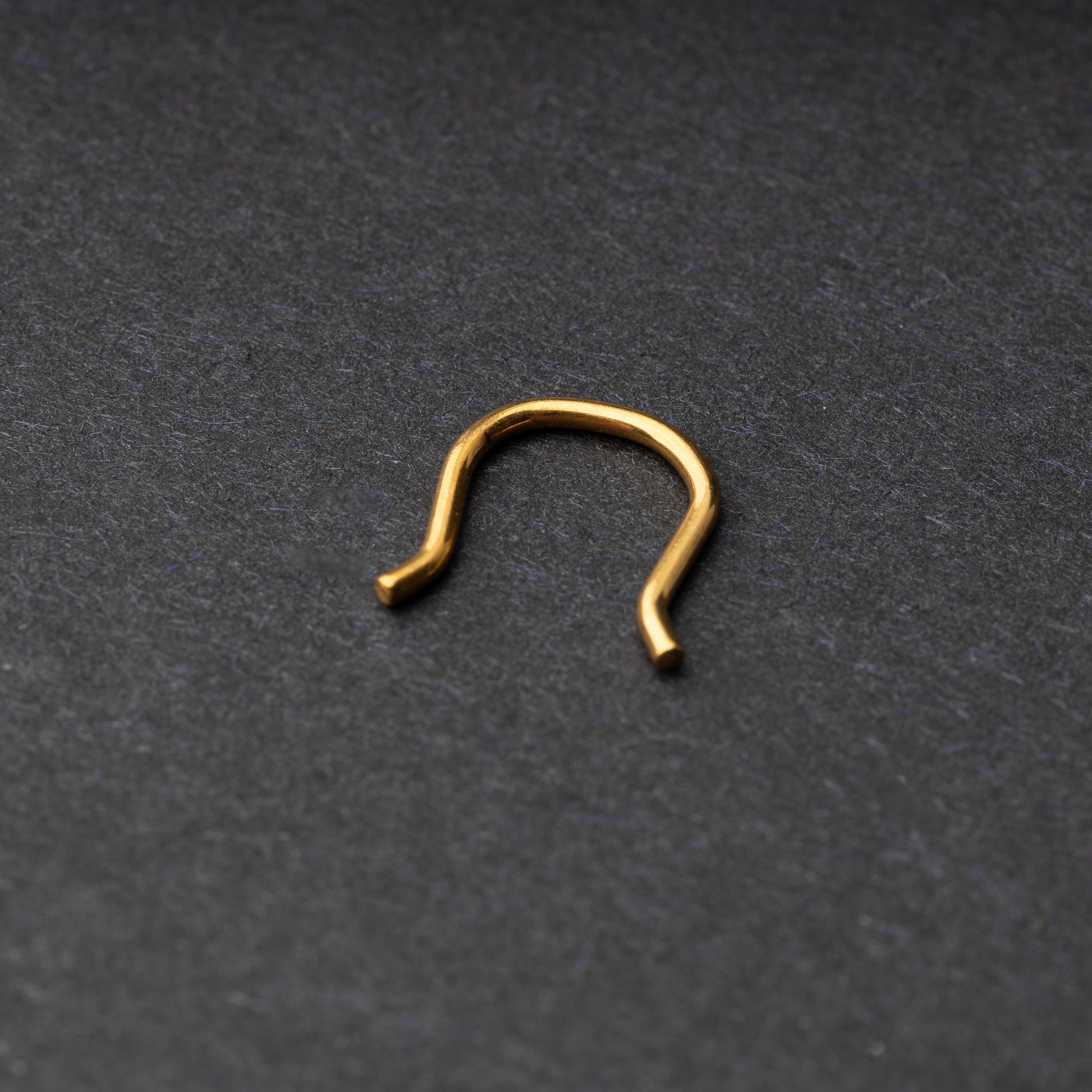 U-shaped septum retainer in gold displayed on a dark background