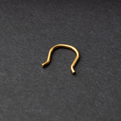 U-shaped septum retainer in gold displayed on a dark background
