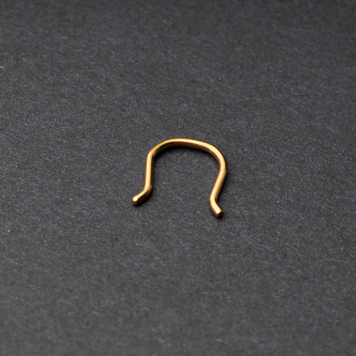 U-shaped septum retainer in rose gold displayed on a dark background