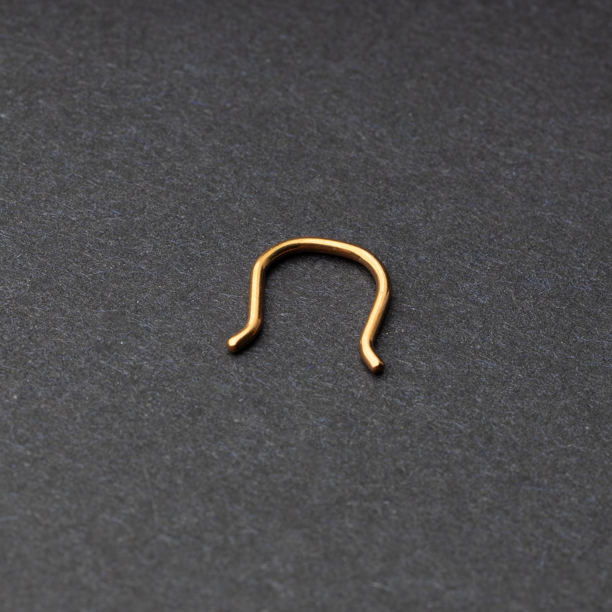 U-shaped septum retainer in rose gold displayed on a dark background