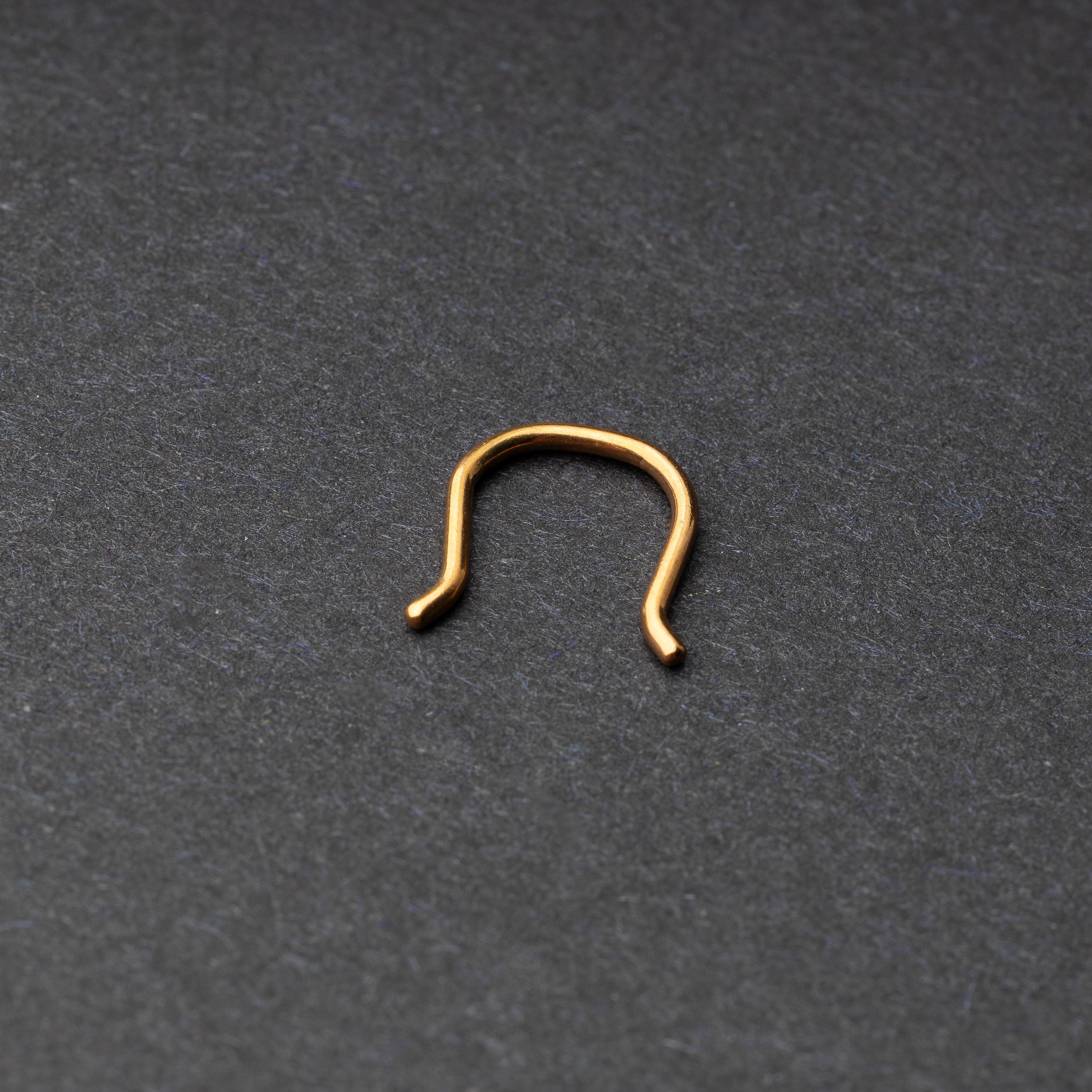 U-shaped septum retainer in rose gold displayed on a dark background