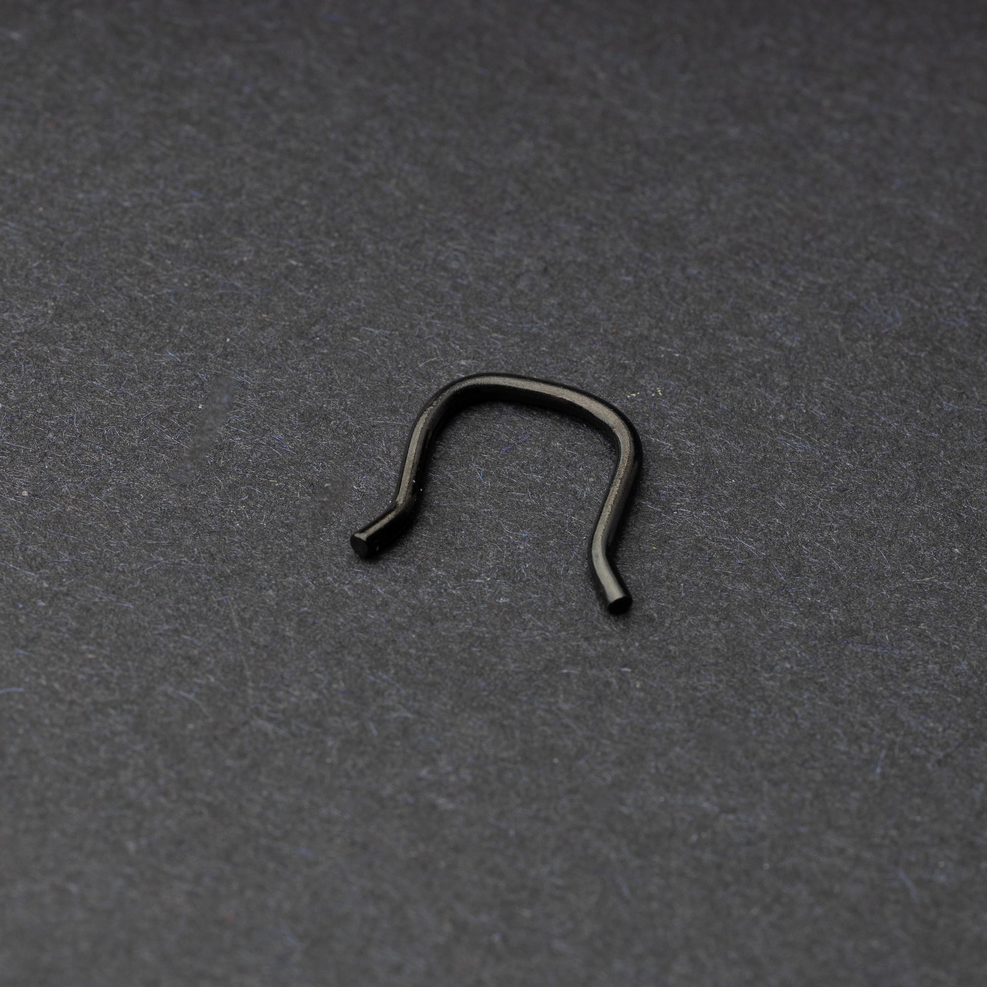U-shaped septum retainer in black displayed on a dark background