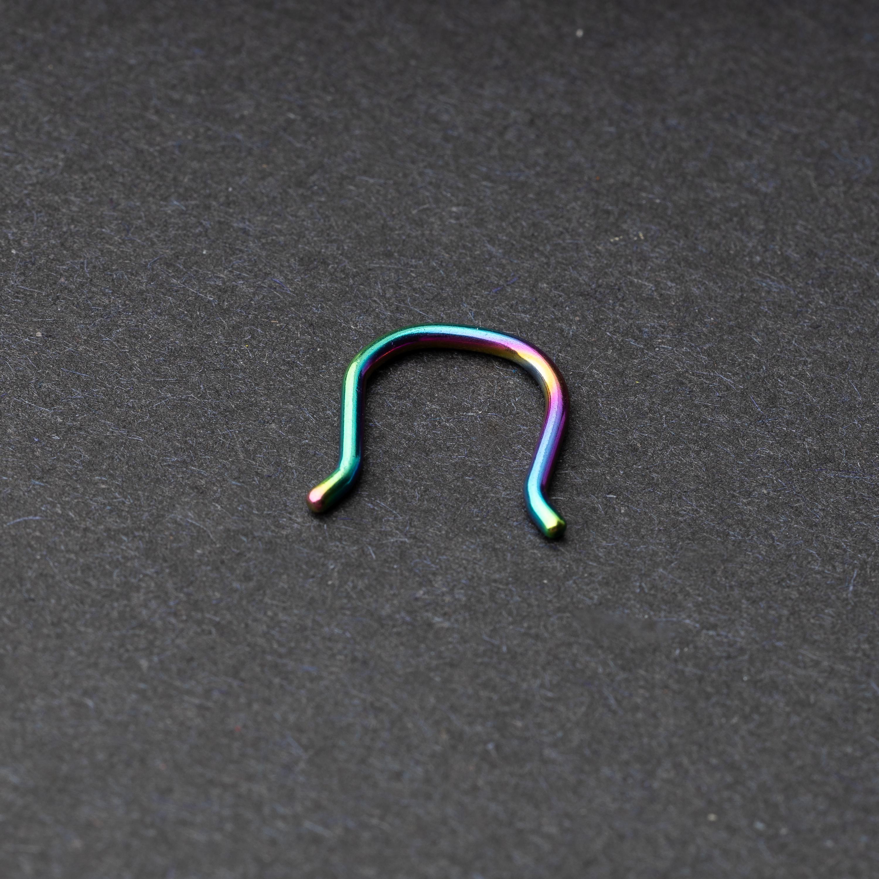 U-shaped septum retainer in rainbow displayed on a dark background