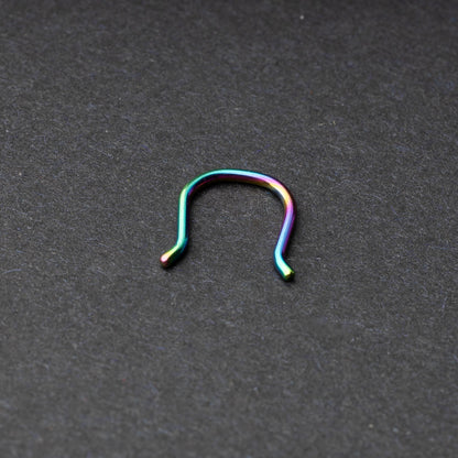 U-shaped septum retainer in rainbow displayed on a dark background