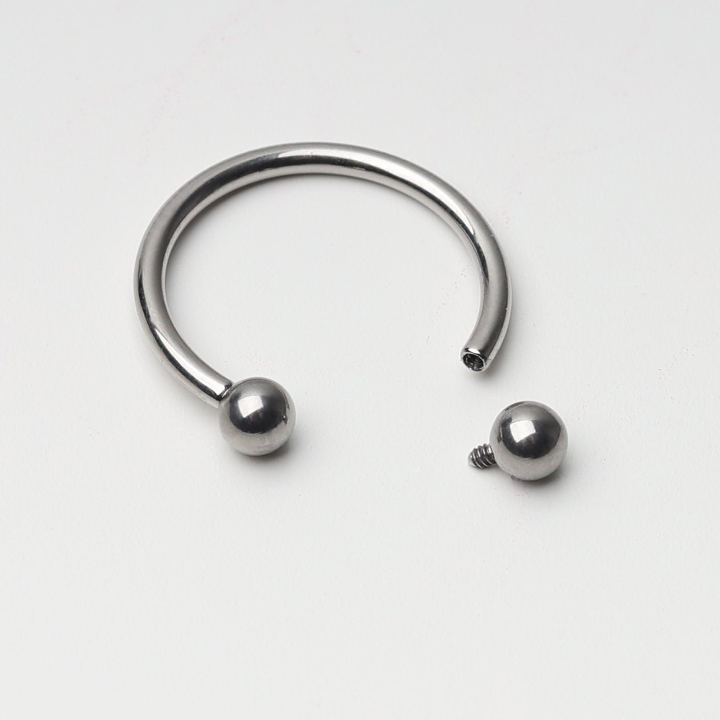 Titanium horseshoe ring with ball ends, displayed on a light background.