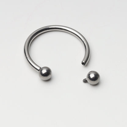 Titanium horseshoe ring with ball ends, displayed on a light background.