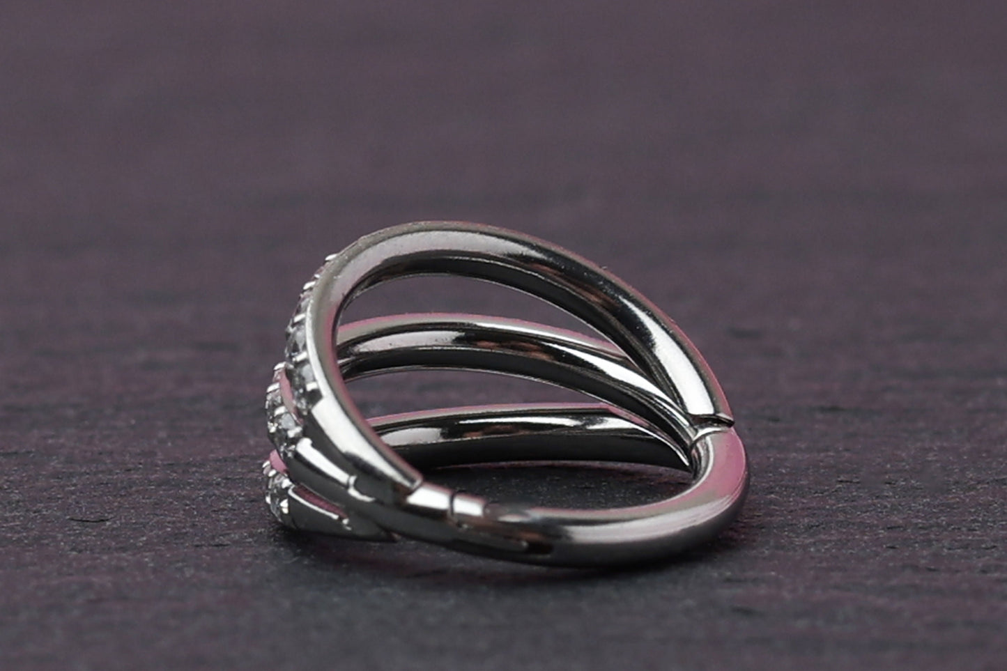 Triple-band clicker ring encrusted with cubic zirconia stones, displayed on a dark background, showcasing its elegant and sparkling design.