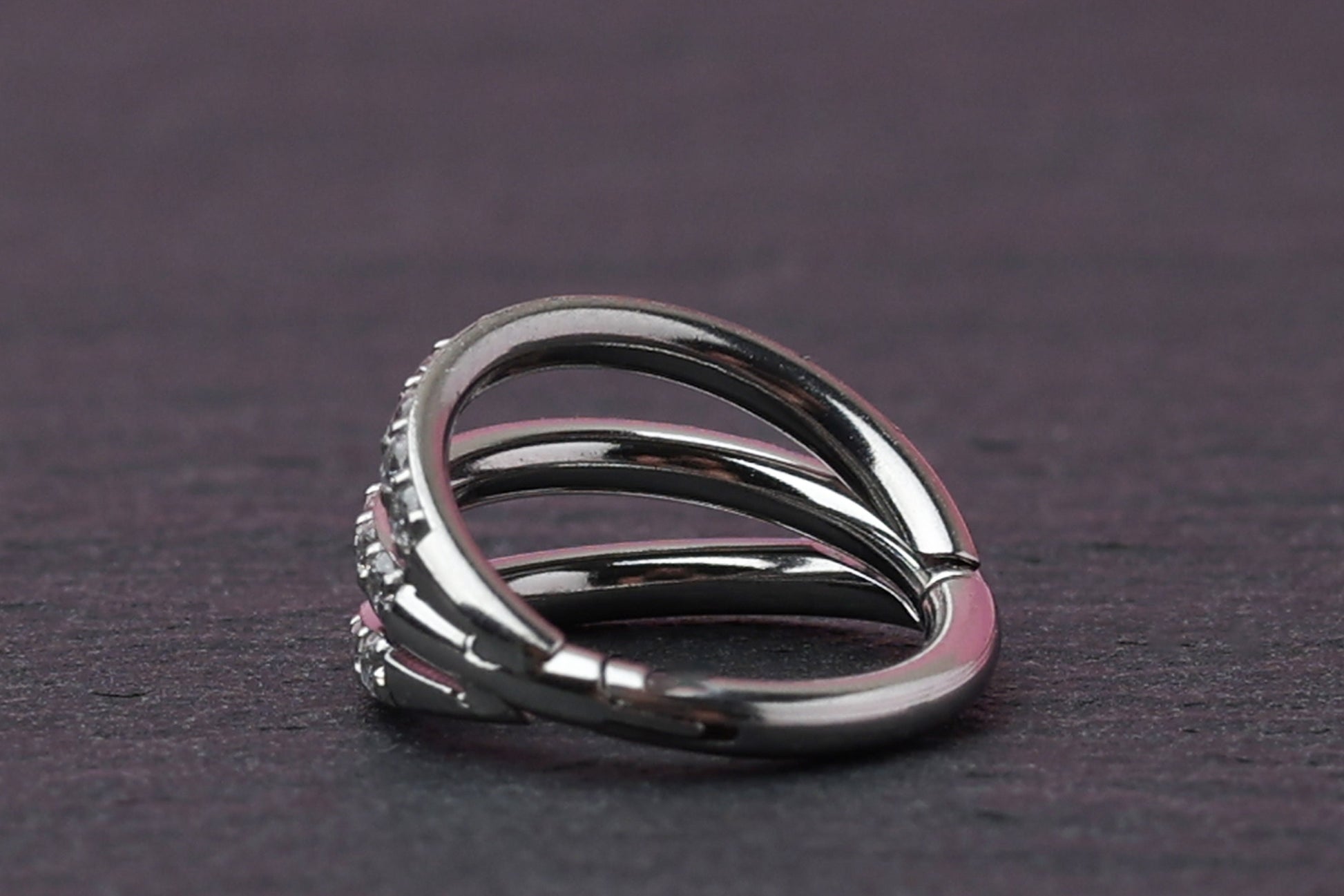 Triple-band clicker ring encrusted with cubic zirconia stones, displayed on a dark background, showcasing its elegant and sparkling design.