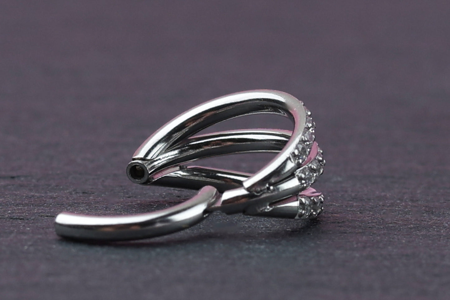 Triple-band clicker ring encrusted with cubic zirconia stones, displayed on a dark background, showcasing its elegant and sparkling design.