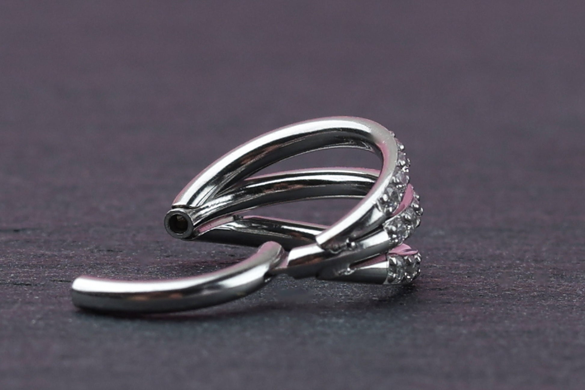 Triple-band clicker ring encrusted with cubic zirconia stones, displayed on a dark background, showcasing its elegant and sparkling design.