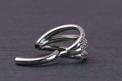 Triple-band clicker ring encrusted with cubic zirconia stones, displayed on a dark background, showcasing its elegant and sparkling design.
