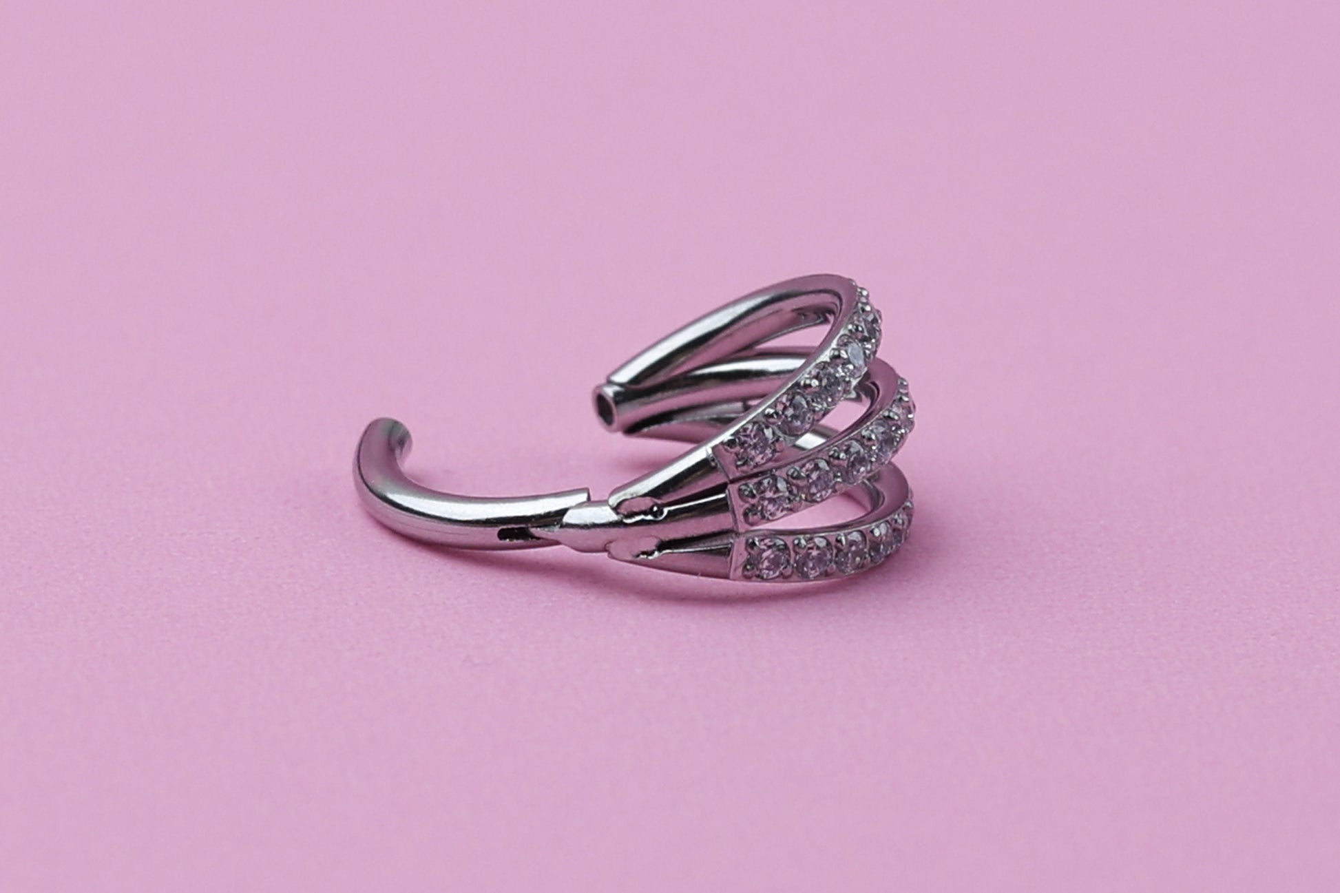 Triple-band clicker ring encrusted with cubic zirconia stones, displayed on a dark background, showcasing its elegant and sparkling design.