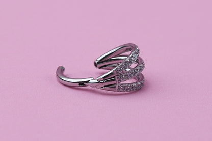 Triple-band clicker ring encrusted with cubic zirconia stones, displayed on a dark background, showcasing its elegant and sparkling design.