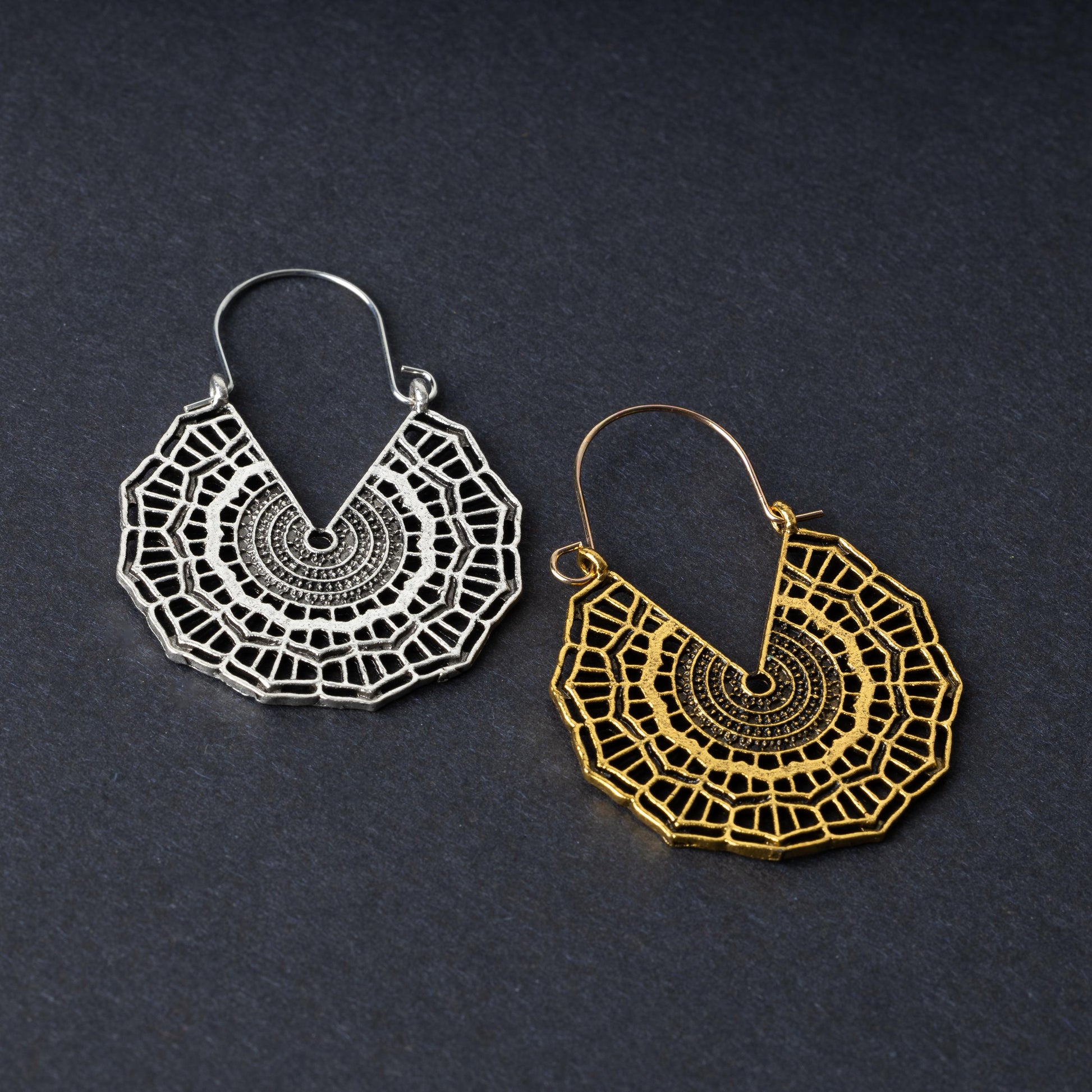 Mandala-inspired earrings in gold and silver finishes with intricate geometric designs, displayed on a dark background.