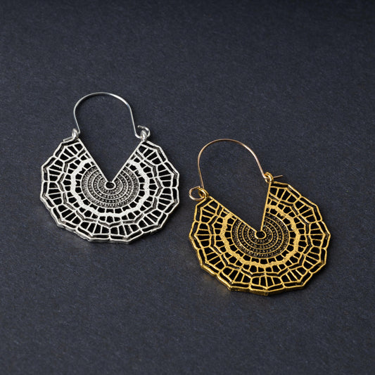 Mandala-inspired earrings in gold and silver finishes with intricate geometric designs, displayed on a dark background.