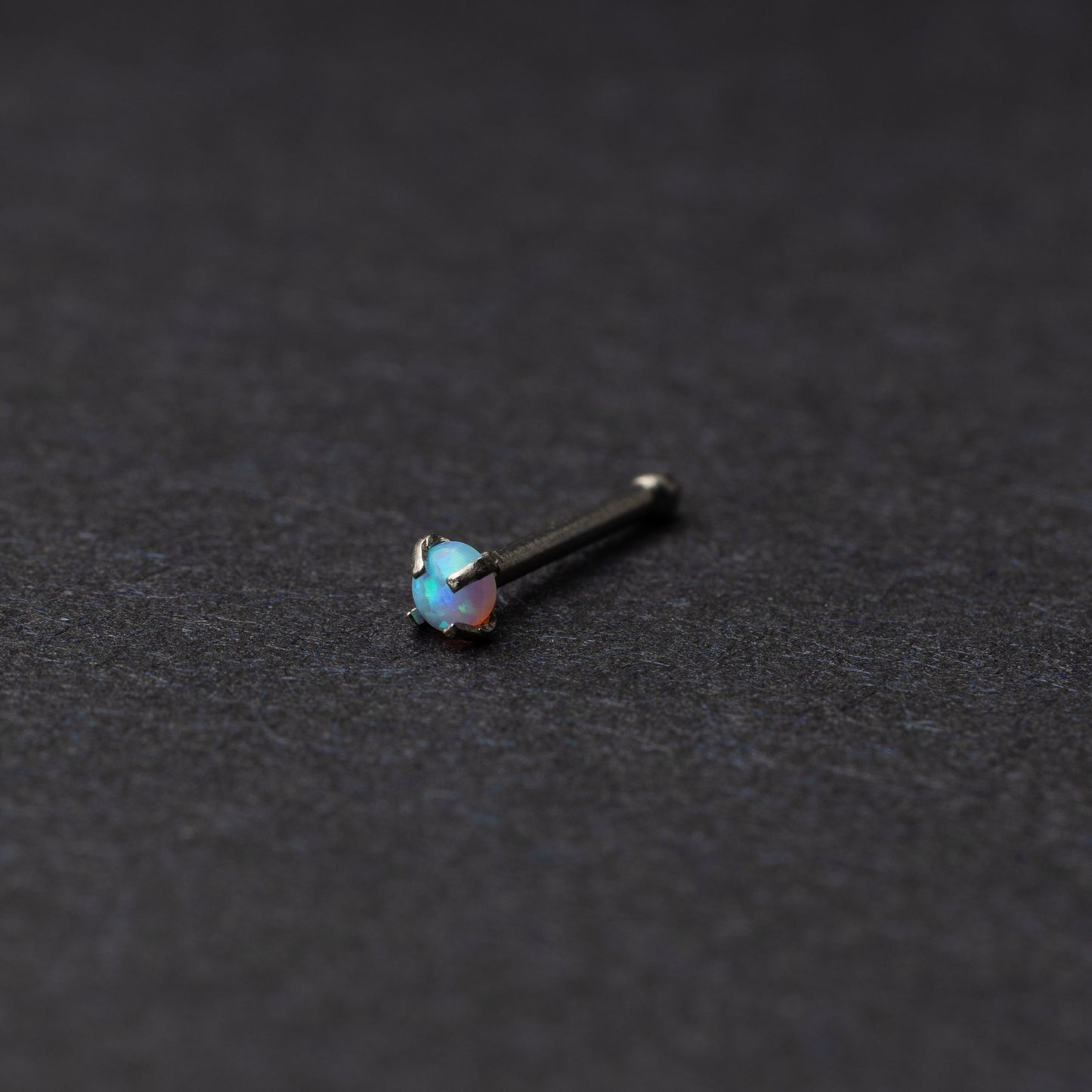 Light blue nose stud displayed on a dark background