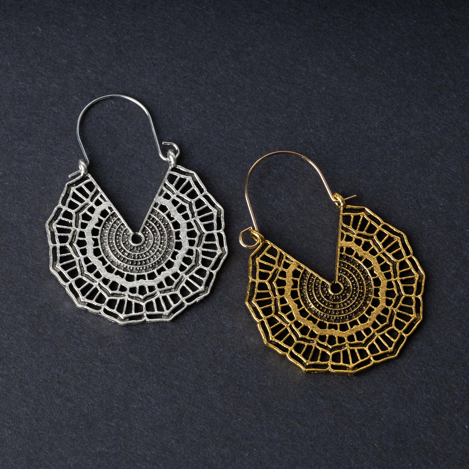 Mandala-inspired earrings in gold and silver finishes with intricate geometric designs, displayed on a dark background.