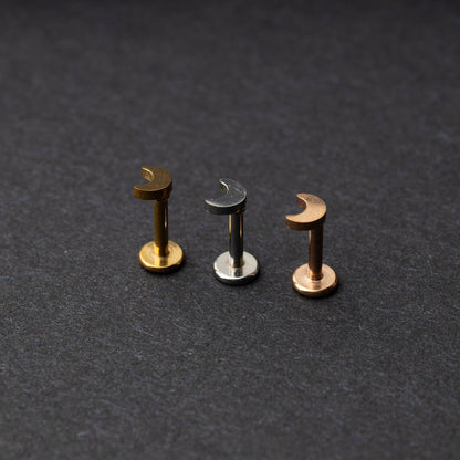 Gold, silver, and rose gold crescent moon labret studs displayed on a dark background.