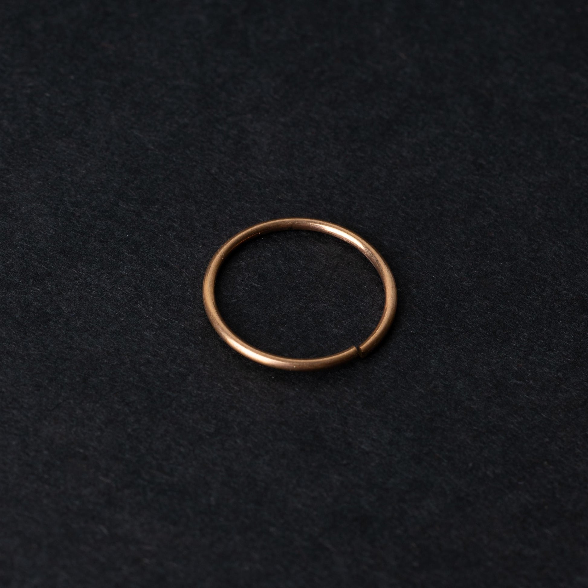 A single thin rose gold seamless hoop with a polished finish, displayed on a dark background.