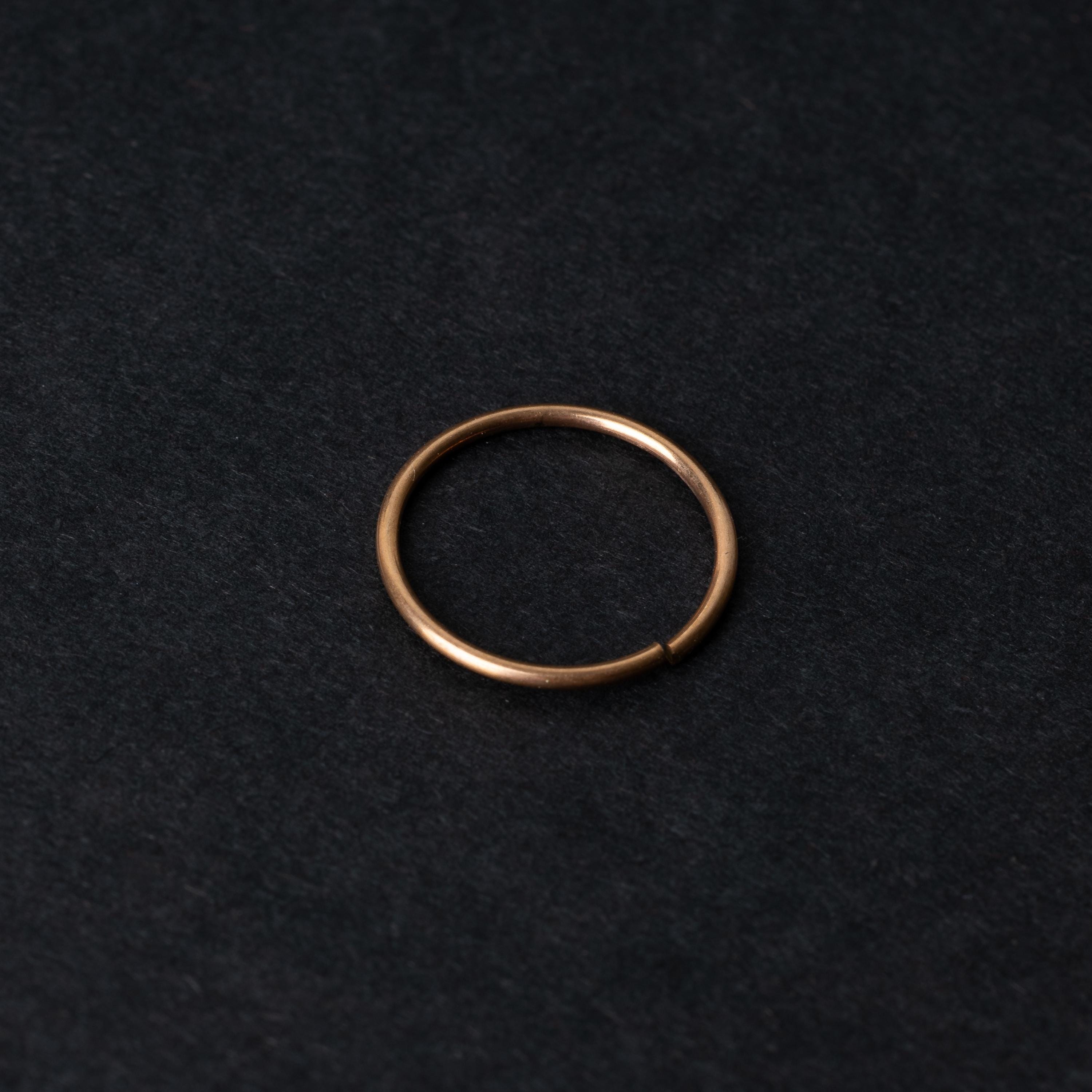 A single thin rose gold seamless hoop with a polished finish, displayed on a dark background.