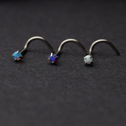 Opalescent nose screws in various colors with a prong setting, displayed on a dark background.