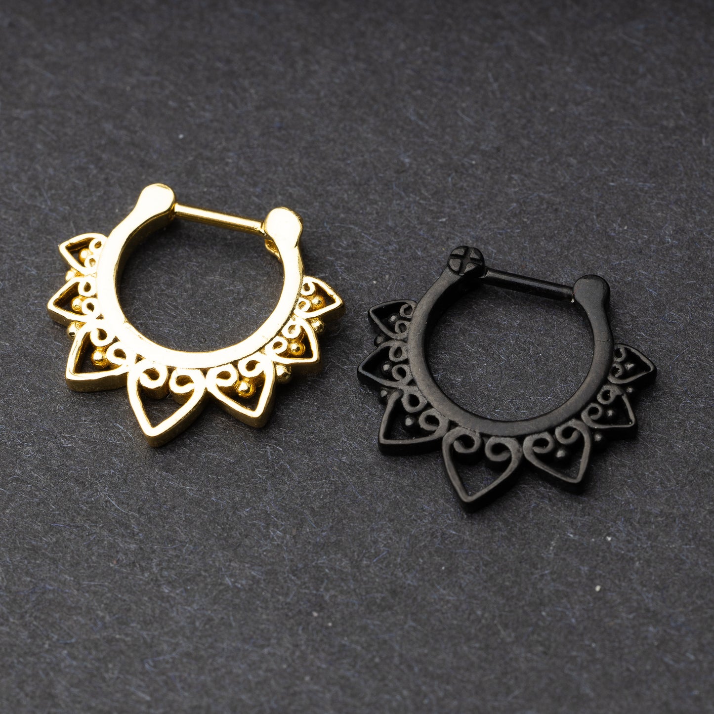 Gold and black septum clickers featuring a bold, geometric design with intricate swirling details. Perfect for adding an edge to your look while maintaining elegance. Designed for septum piercings.