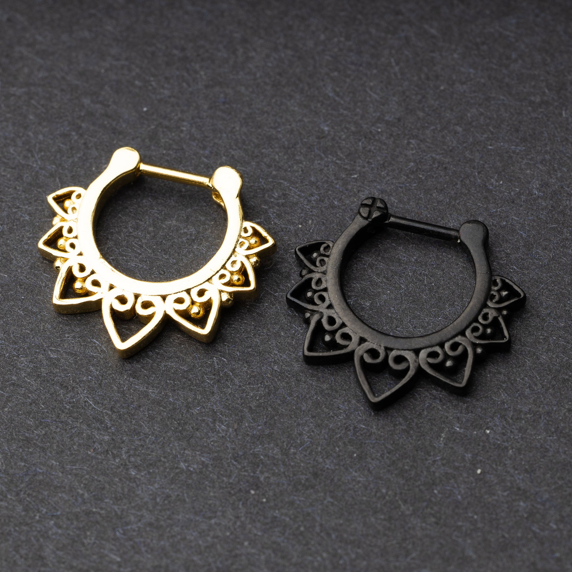 Gold and black septum clickers featuring a bold, geometric design with intricate swirling details. Perfect for adding an edge to your look while maintaining elegance. Designed for septum piercings.