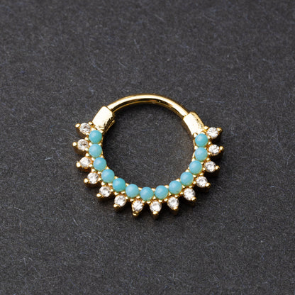 Gold-tone septum clicker with turquoise beads and cubic zirconia stones arranged in an elegant pattern, displayed on a dark background.