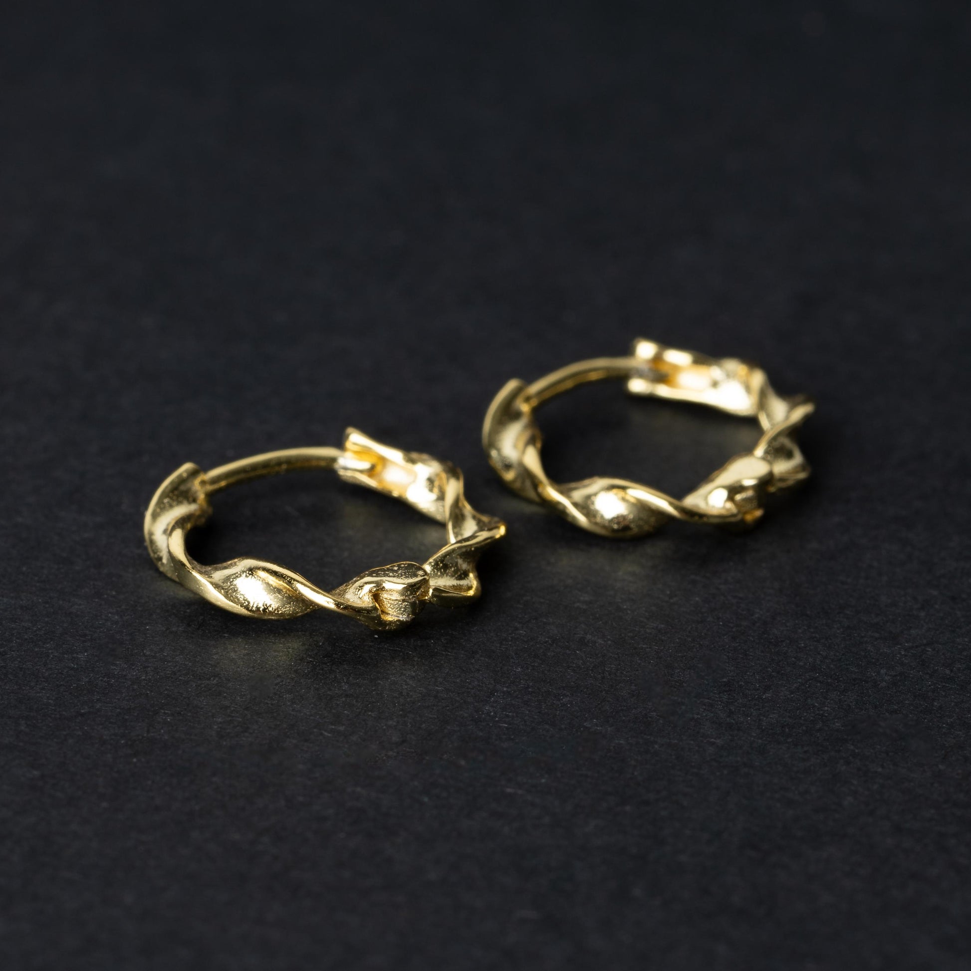 Gold-toned twisted rope design clickers made from 925 sterling silver, displayed on a black background.