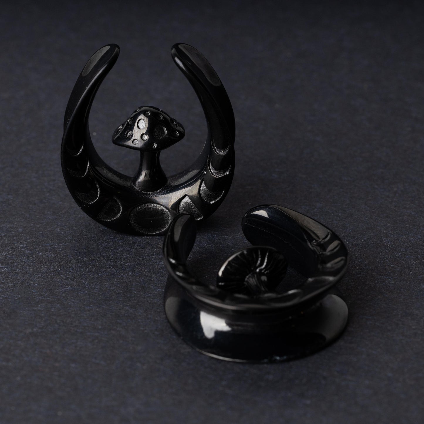 Pair of crescent moon tunnels with mushroom detailing in black, displayed on a dark background.