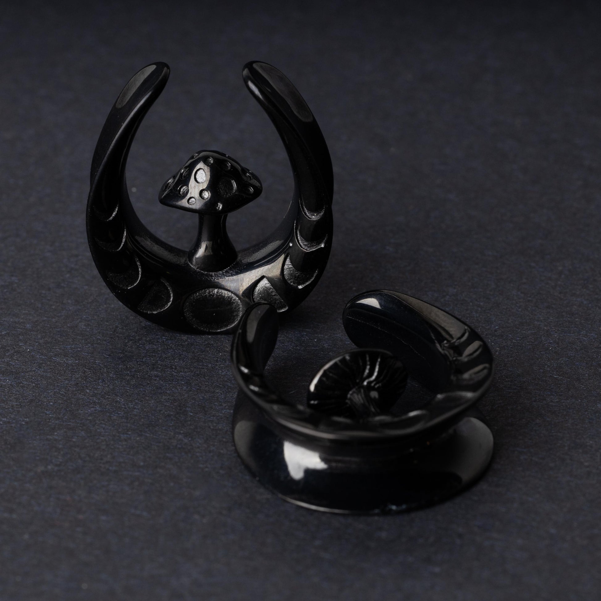 Pair of crescent moon tunnels with mushroom detailing in black, displayed on a dark background.