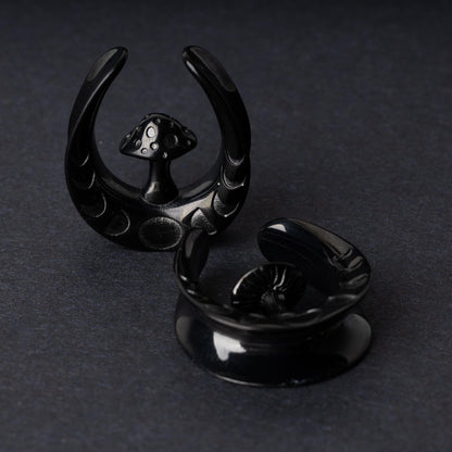 Pair of crescent moon tunnels with mushroom detailing in black, displayed on a dark background.