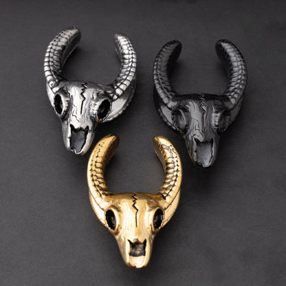 Three ram skull saddle tunnels in black, silver, and gold finishes, showcasing intricate skull details and bold design on a dark background.