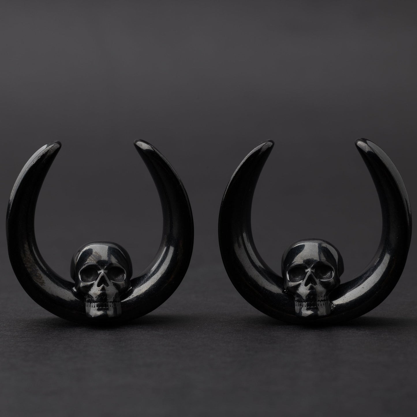 Pair of Skull design saddle tunnels in black, displayed on a dark background.