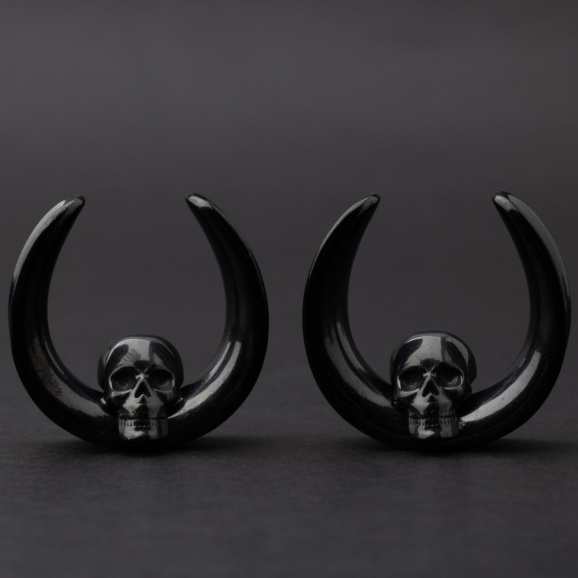 Pair of Skull design saddle tunnels in black, displayed on a dark background.