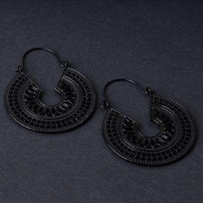 Pair of black hoop earrings with intricate cutout details and textured patterns, displayed on a dark background.