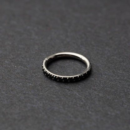 A textured stainless steel seamless ring with a polished finish, placed on a dark, textured background.