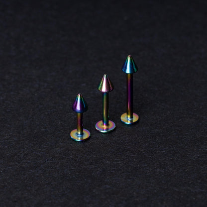 Three rainbow labret studs with cone-shaped tops displayed on a dark background, highlighting their iridescent finish and sleek, durable design.