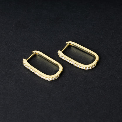 Pair of rectangular gold hoop earrings with crystal embellishments, displayed on a dark background.