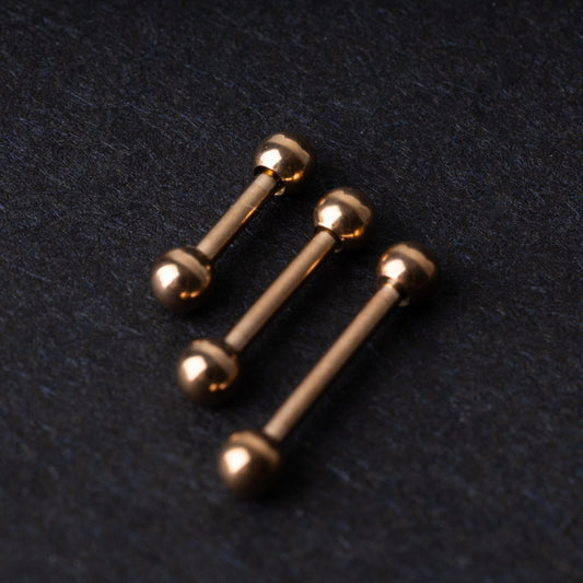 Rose Gold-tone stainless steel barbells on a dark background.