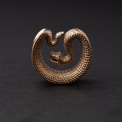 Rose Gold Gold Snake-shaped saddle plugs, displayed on a dark background.