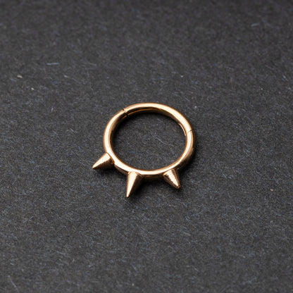 Rose Gold-tone stainless steel clicker ring with three spikes, displayed on a dark textured background.