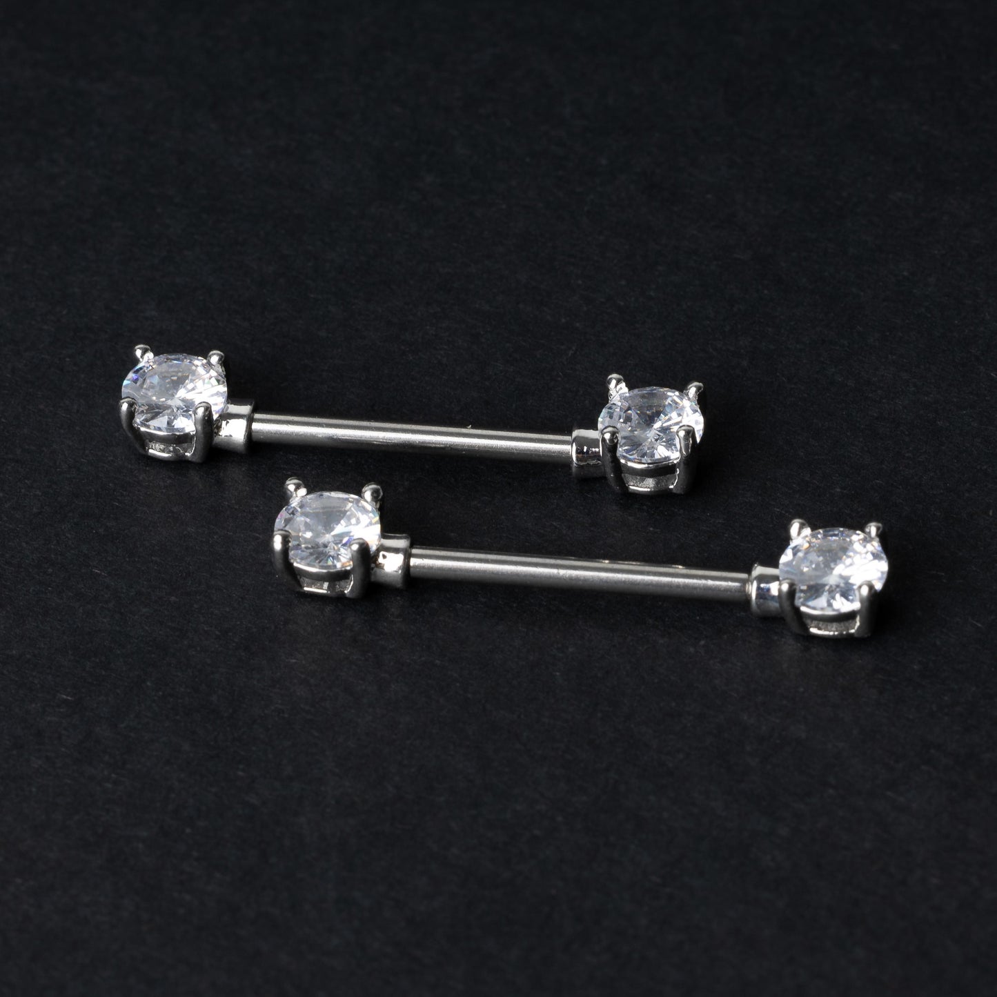 Crystal-studded barbells in silver displayed on a dark background.