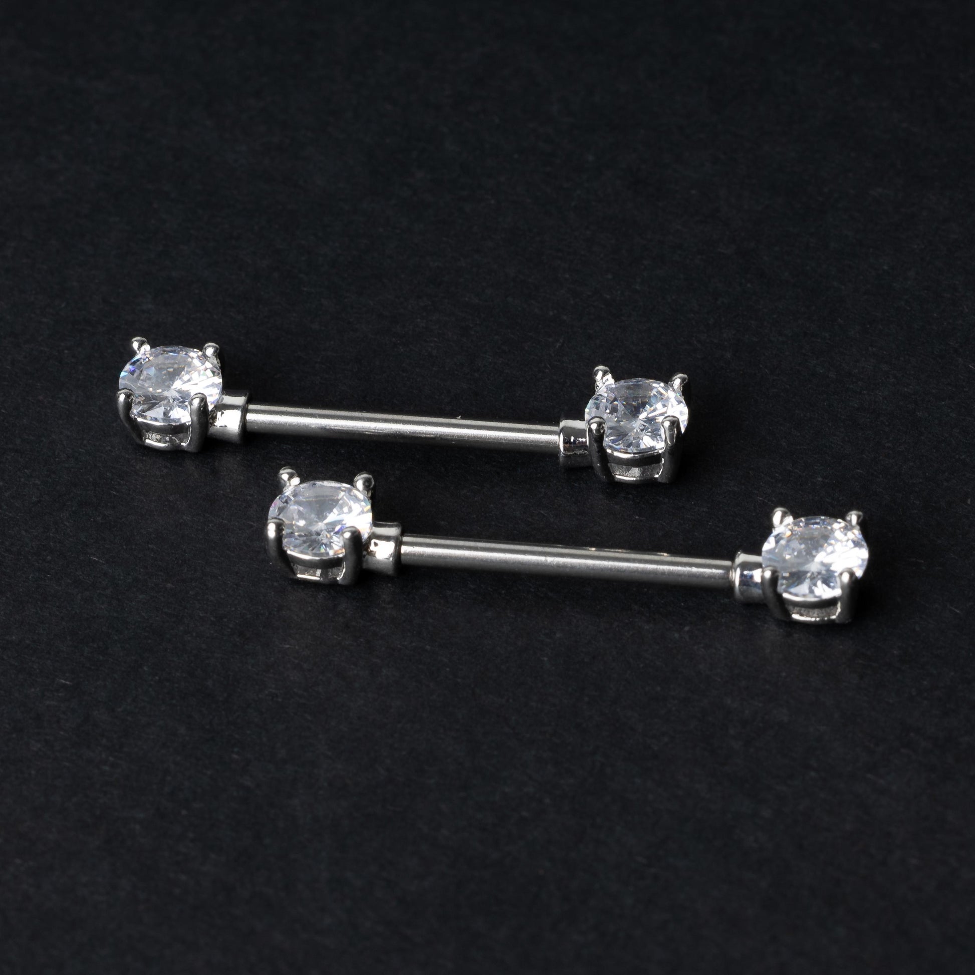 Crystal-studded barbells in silver displayed on a dark background.