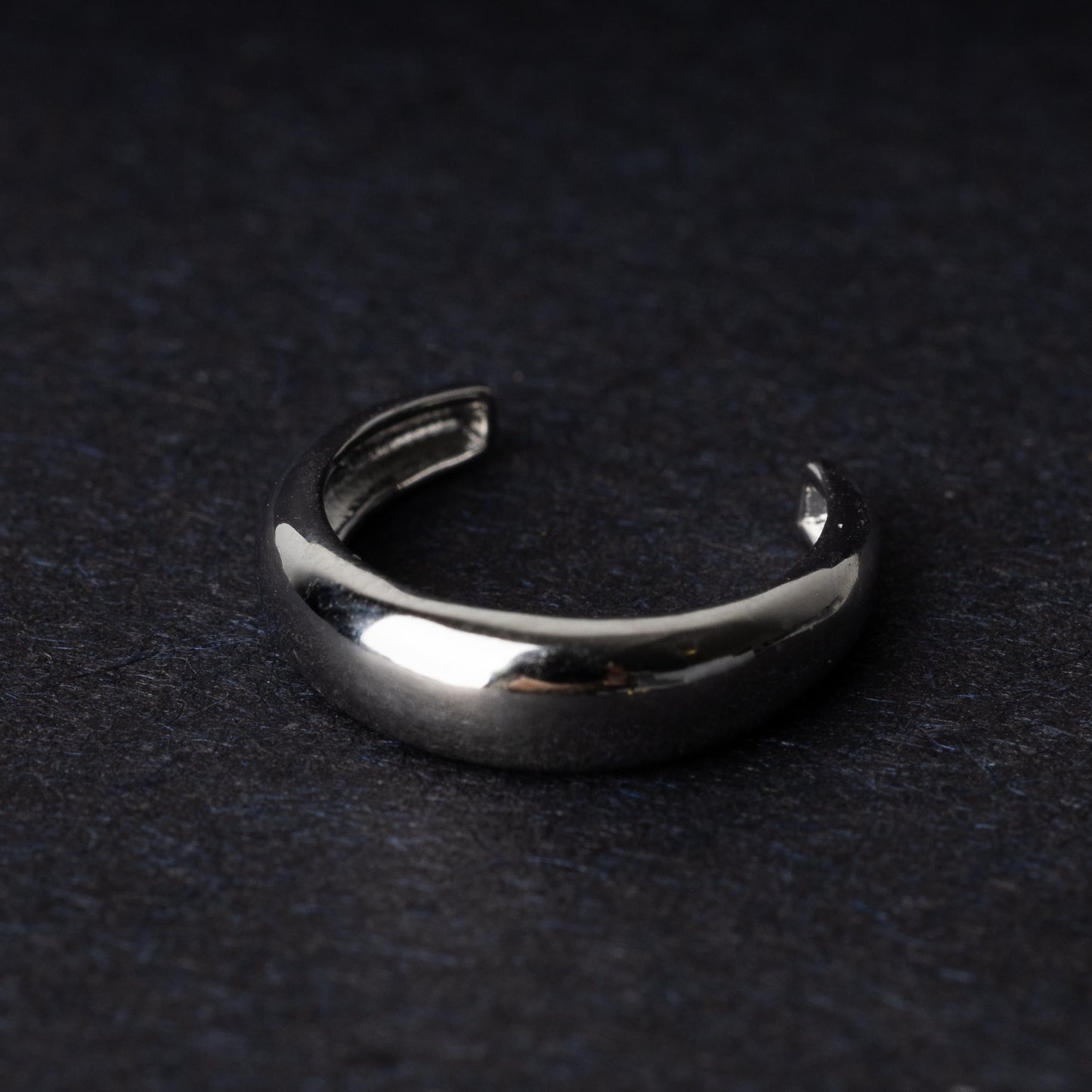 Bold ear cuff in silver with a smooth, domed design, displayed on a dark background.
