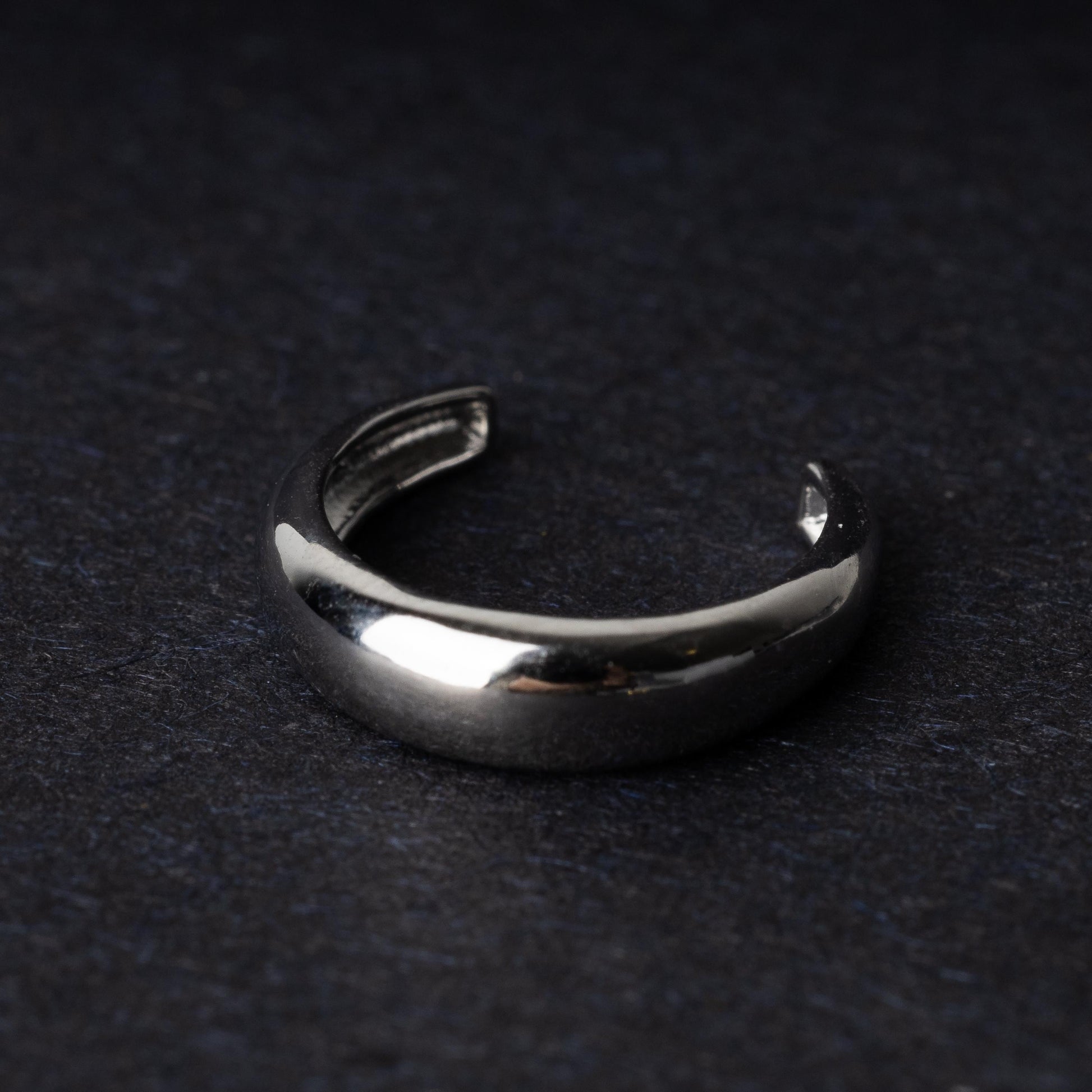 Bold ear cuff in silver with a smooth, domed design, displayed on a dark background.
