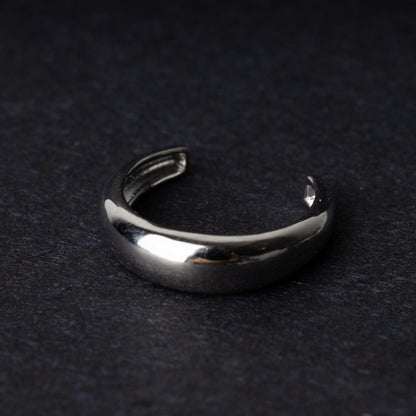 Bold ear cuff in silver with a smooth, domed design, displayed on a dark background.