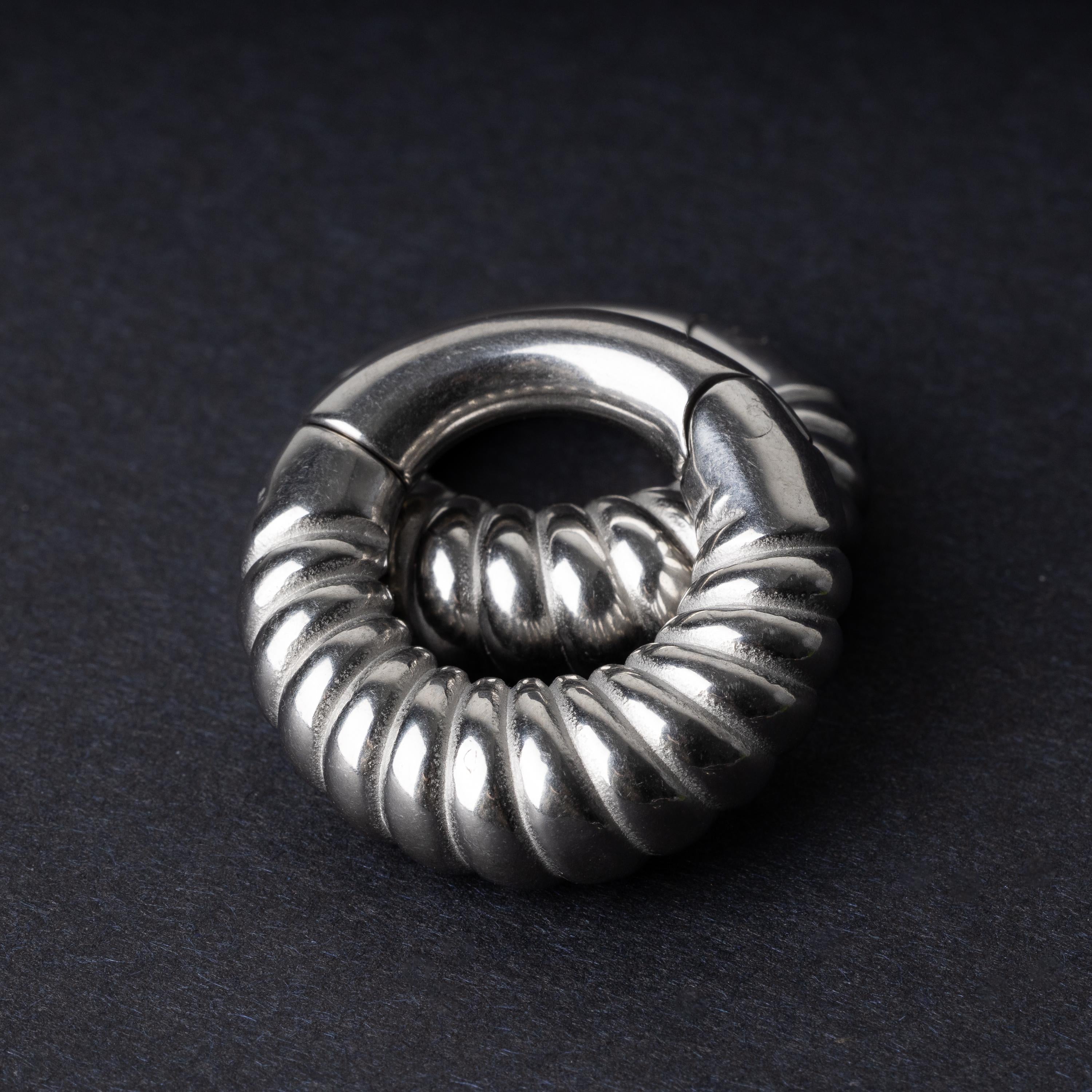 Silver textured hoop rings with a ridged design on a dark background.