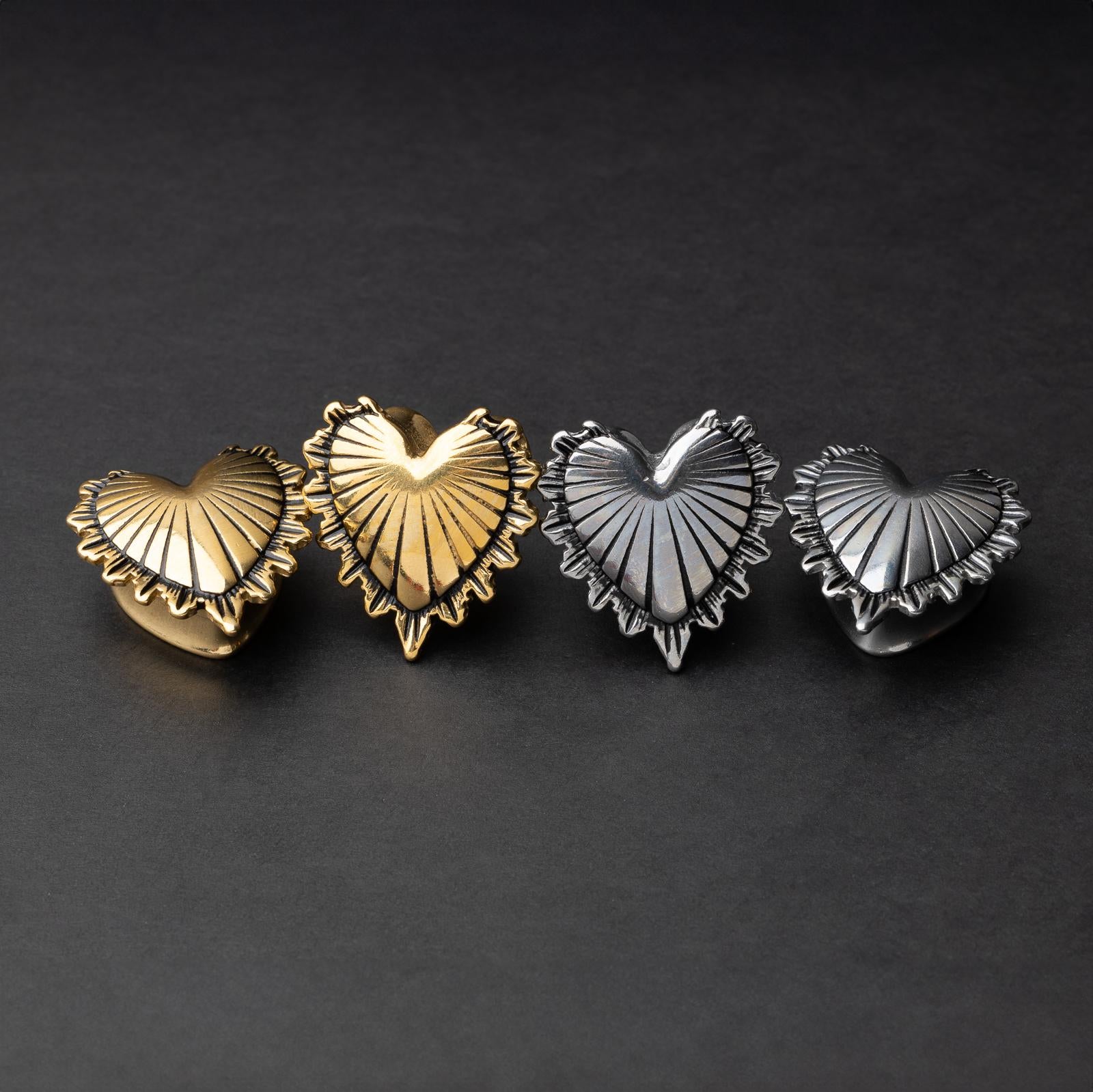 Sacred Heart plugs in gold and silver finishes, showcasing intricate 3D heart designs with a radiant pattern, displayed on a matte dark background.